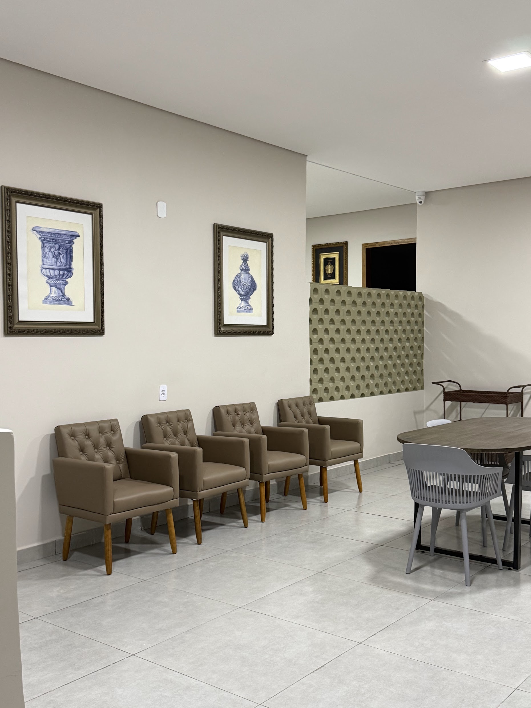 Sala de visitas com poltronas marrons e quadros de gravuras clássicas